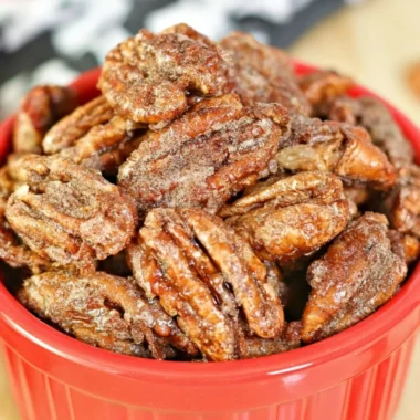 Bowl of air fryer candied pecans topped with a sprinkle of sugar