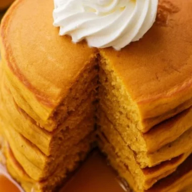 Fluffy pumpkin pancakes stacked with maple syrup and spices
