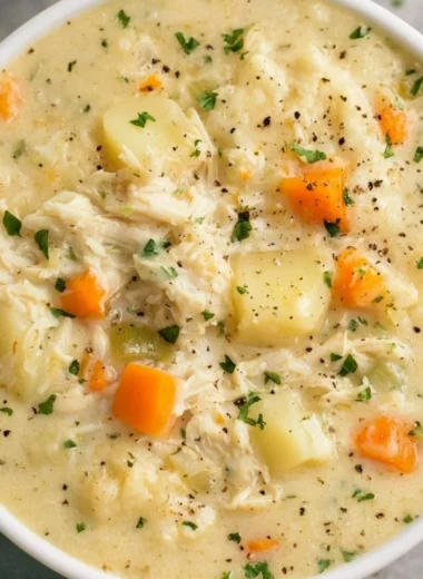 High protein chicken pot pie soup in a bowl with fresh herbs on top.