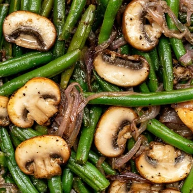 Plate of green beans with sautéed mushrooms garnished with herbs
