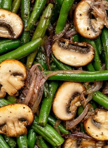 Plate of green beans with sautéed mushrooms garnished with herbs