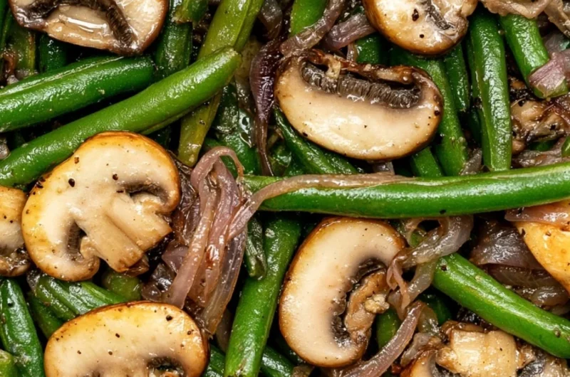 Plate of green beans with sautéed mushrooms garnished with herbs